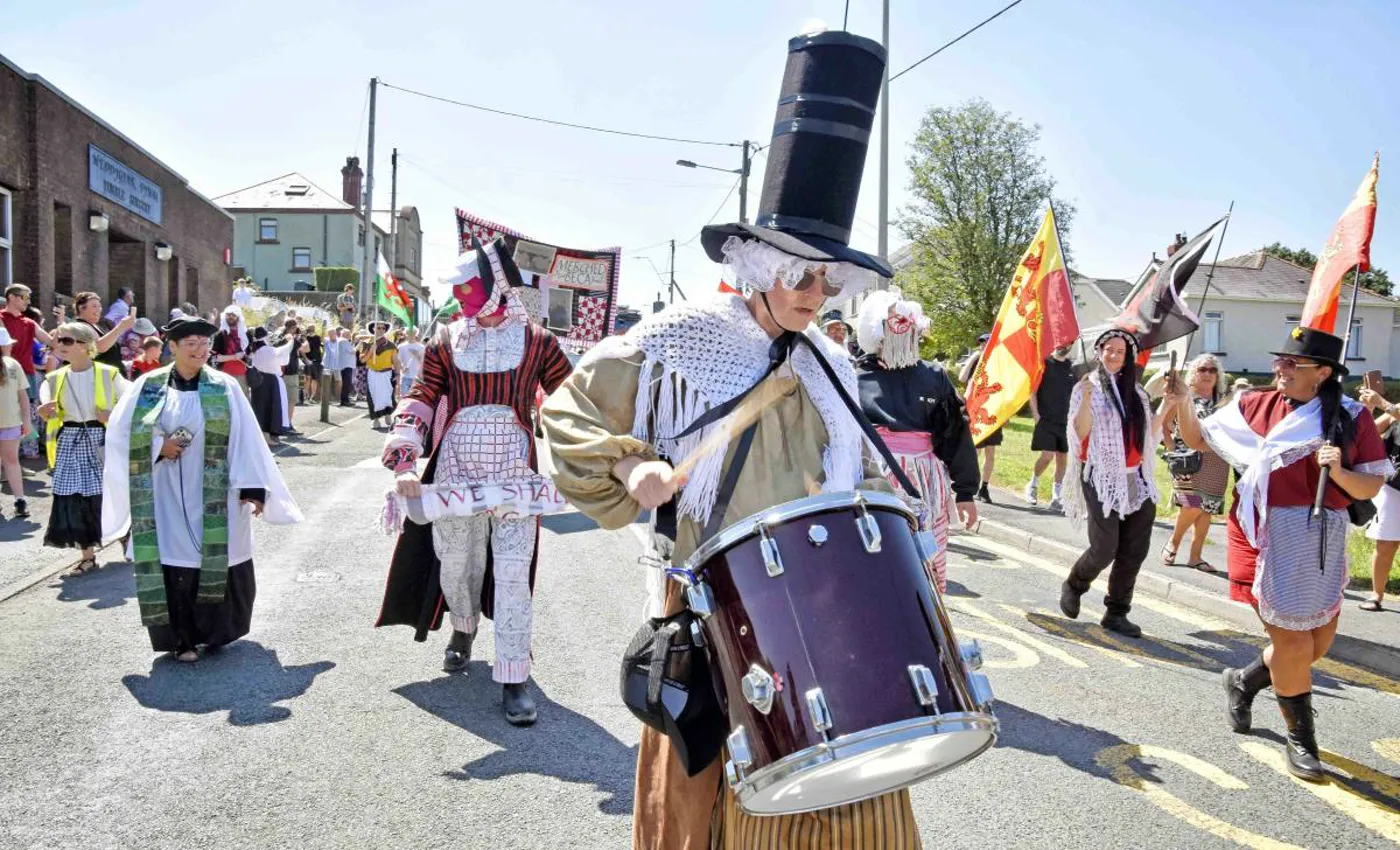 The Gwyl Tyisha parade moving through Tumble, drums and top hats and Rebecca costume